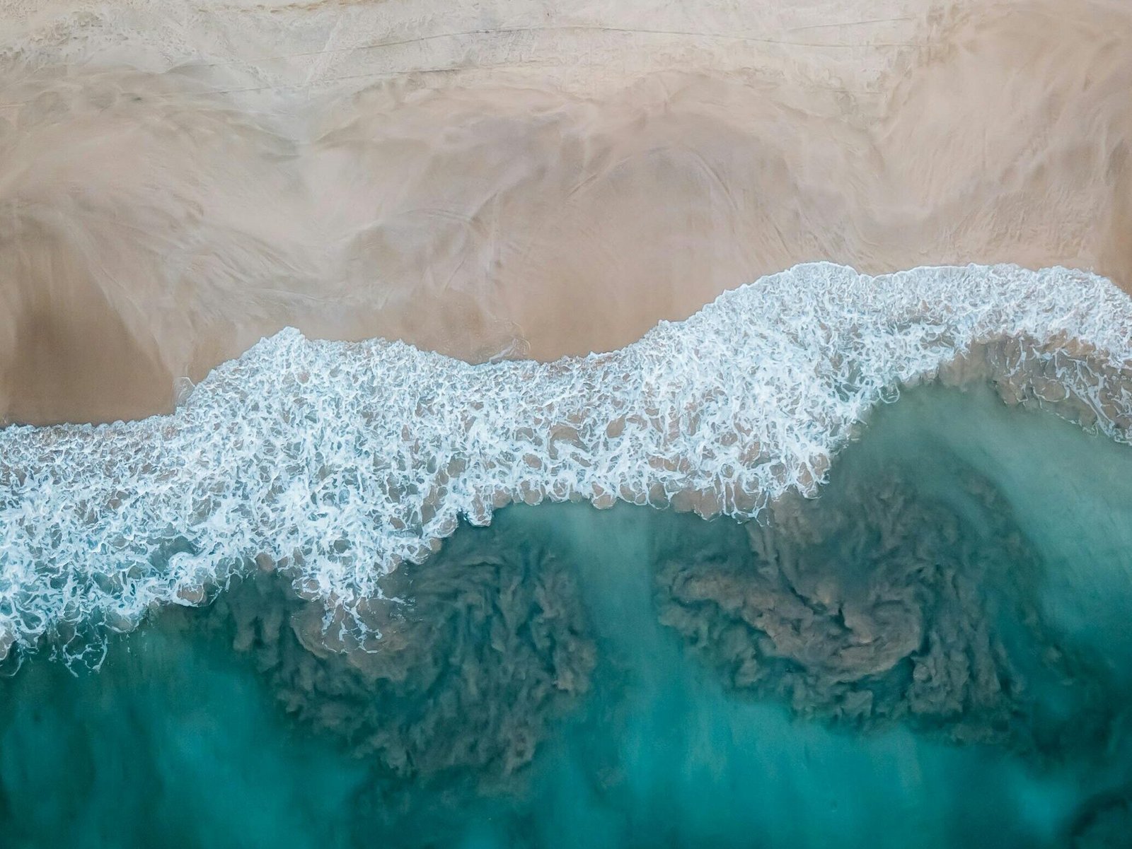 A stunning aerial view showcasing a sandy beach meeting the turquoise ocean waves. Perfect for travel and nature themes.